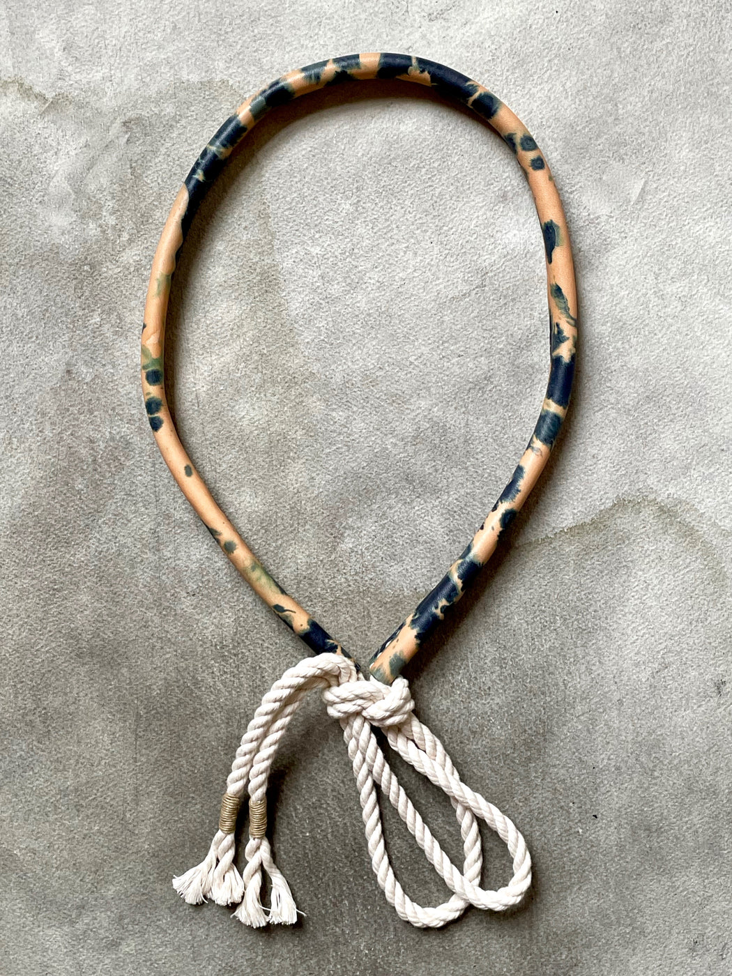 An indigo-dyed natural leather belt with a bow, featuring a rope strap and traditional saddle-making techniques.